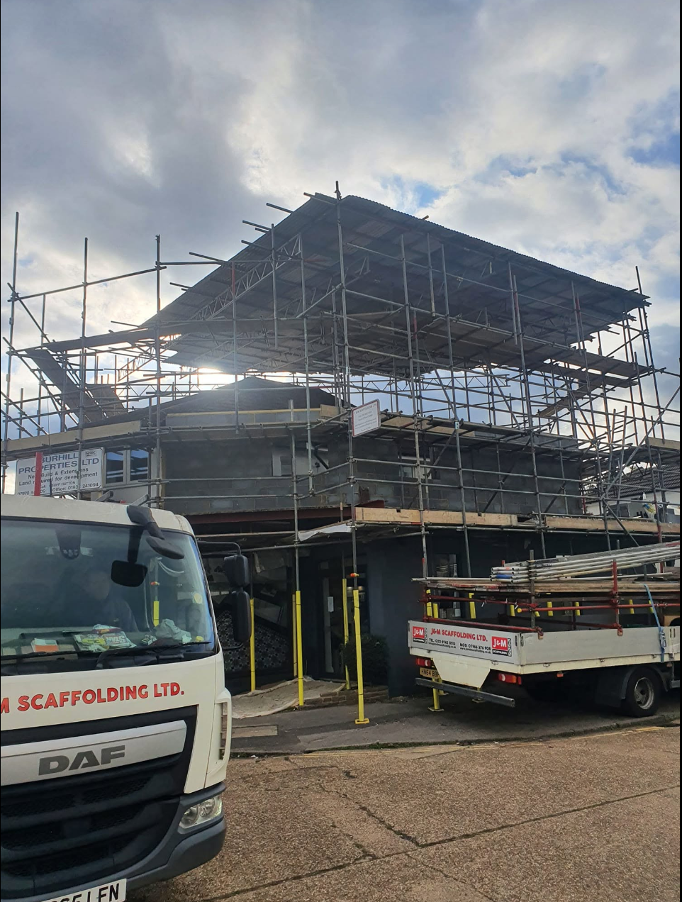Commercial building with large-span sheeted temporary roof and J&M Scaffolding truck loading out